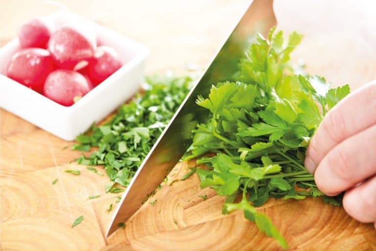 Chopping-fresh-parsley-using-chef's-knife-on-a-chopping-board.-How-Long-Is-A-Chef's-Knife, How Long Is A Chef's Knife?