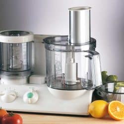 Food processor mixer with tomato, broccoli, lemon and onion on wooden table, 11 Types Of Food Processor Blades And How To Use Them