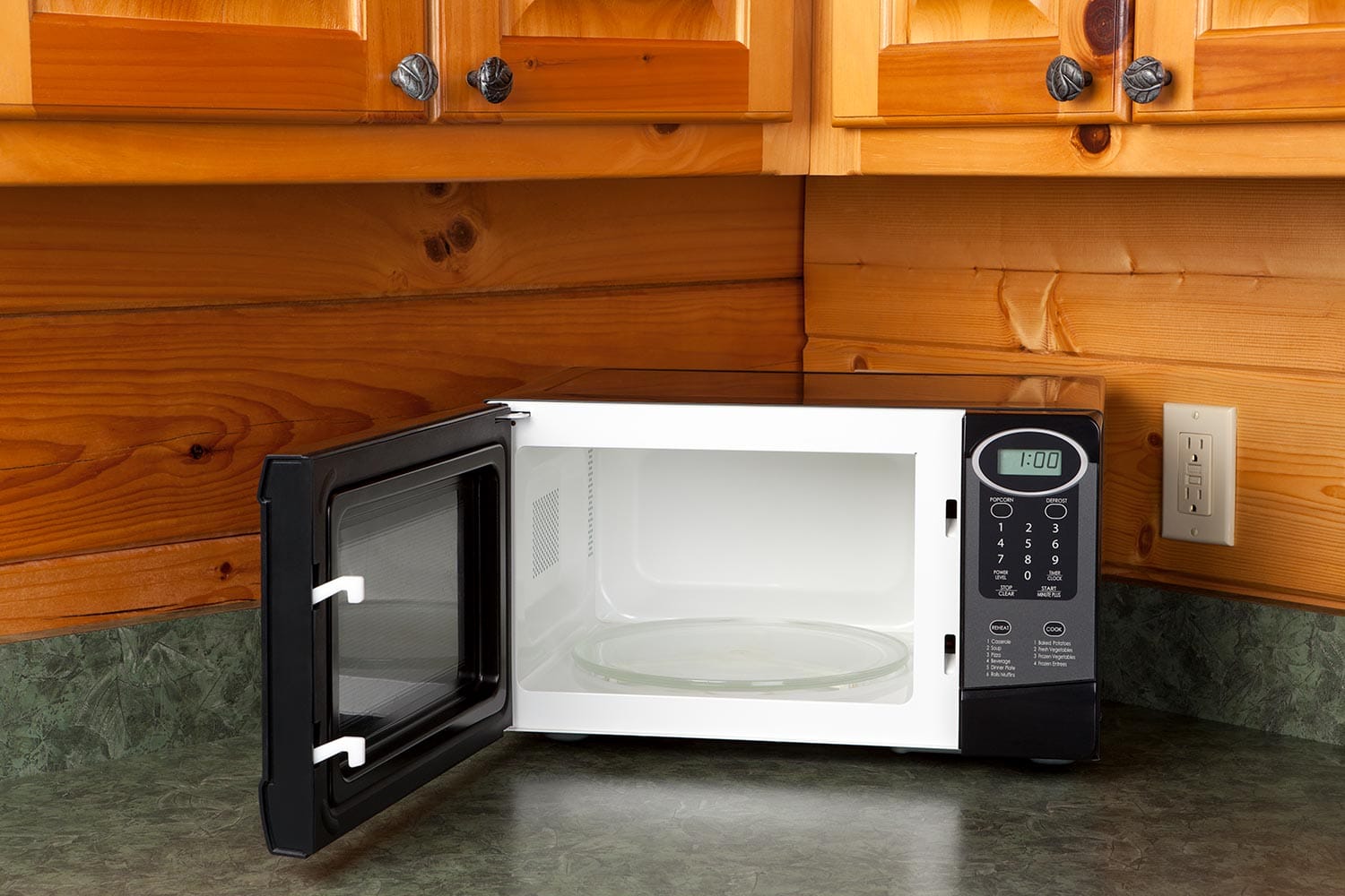 Open microwave oven on a kitchen counter in a log home