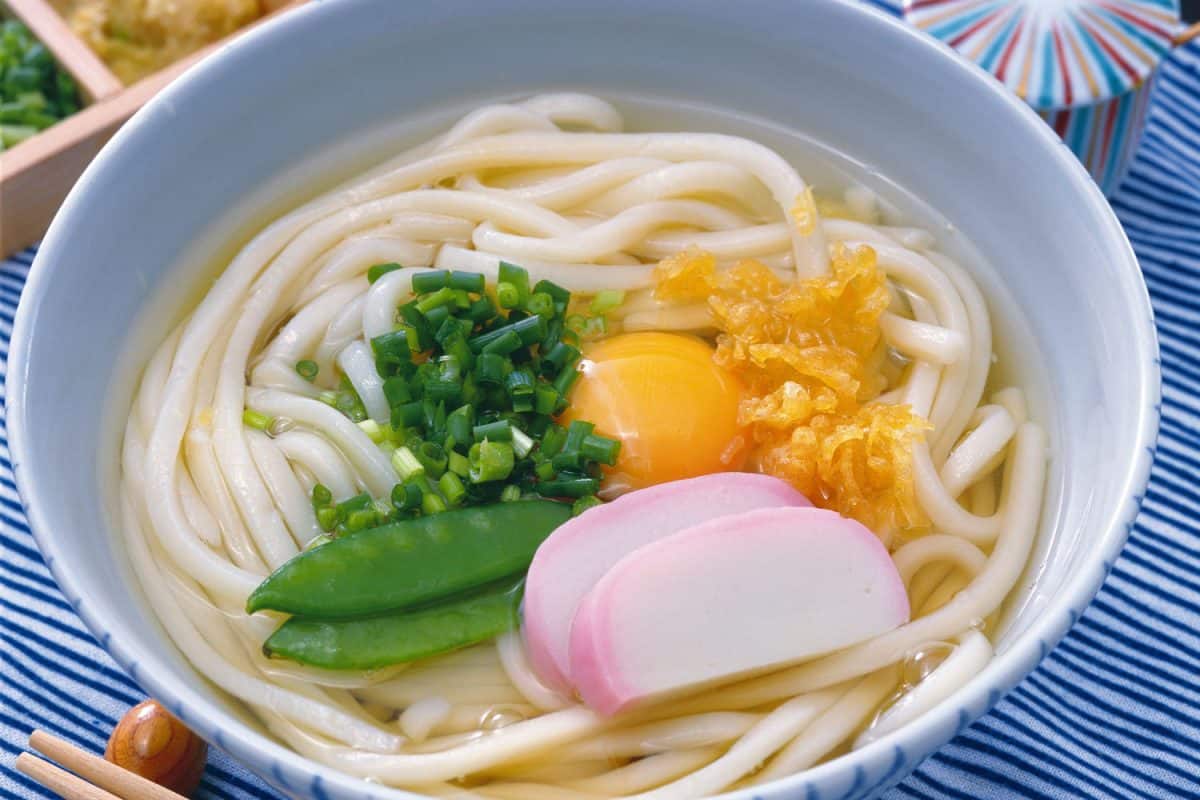 A delicious bowl of Udon noodles with raw eggs garnished with scallions