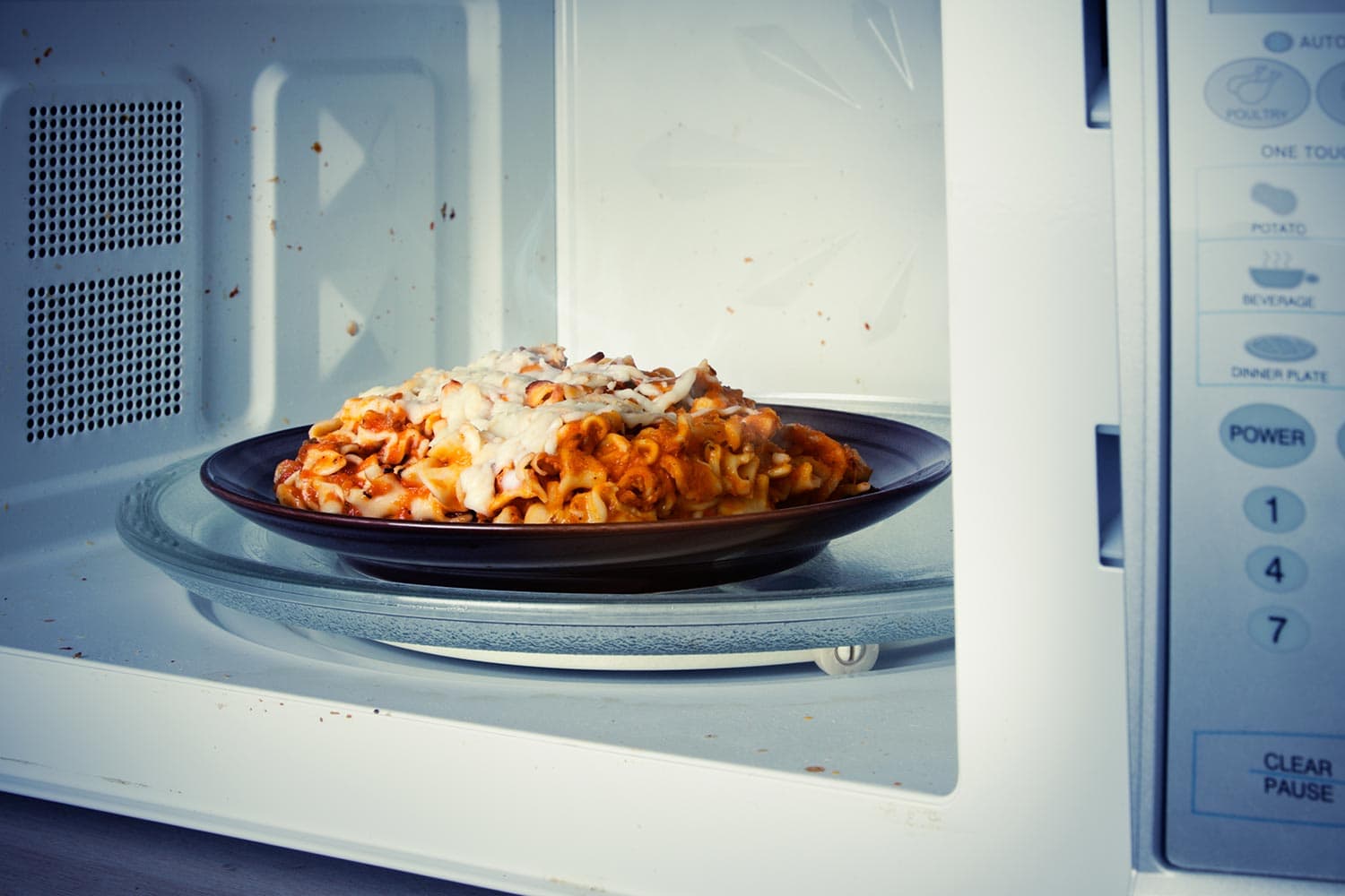 A plate of leftover lasagna is reheated in a microwave