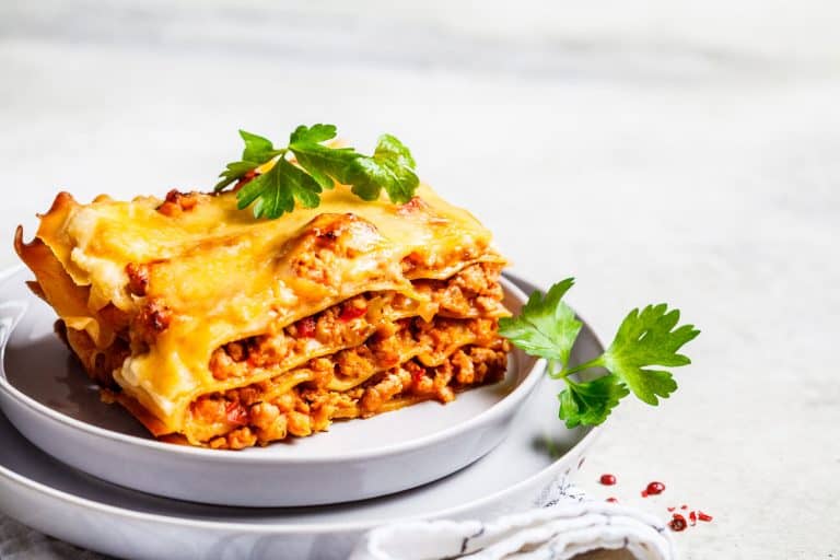 A slice of classic lasagna placed on a small plate, What Temperature Should You Bake Lasagna At? [And What Temperature To Reheat?]