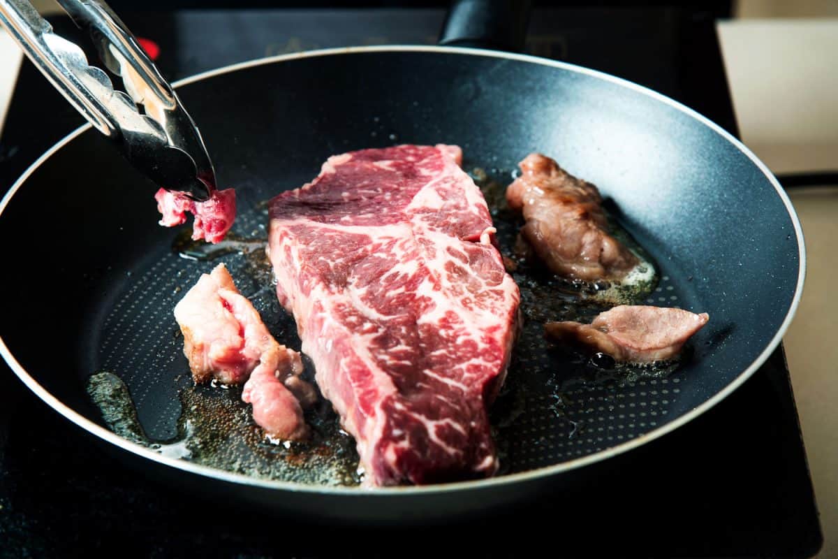 A woman cooking a delicious cut of beef 