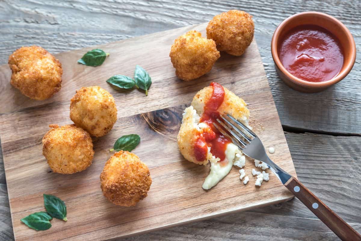 Arancini rice balls with mozzarella cheese served on a chopping board