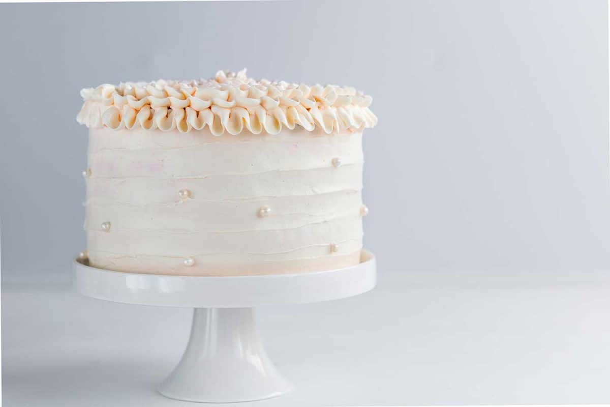 Beautiful birthday cake decorate with edible pearls on white neutral background