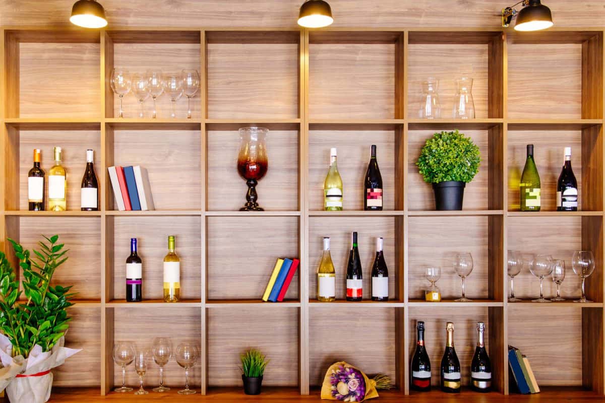 Bottles of white and red wine on a wooden shelf with books in private winery cabinet room