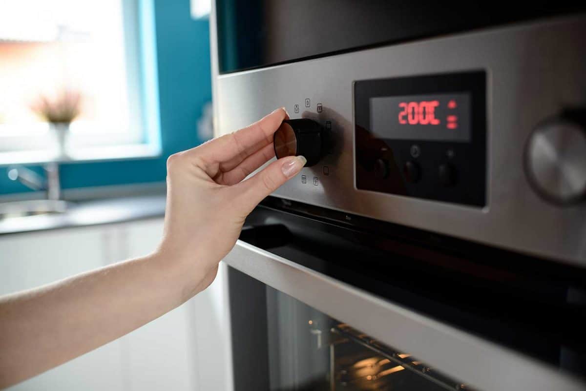 Close up of woman's hand setting temperature control on oven