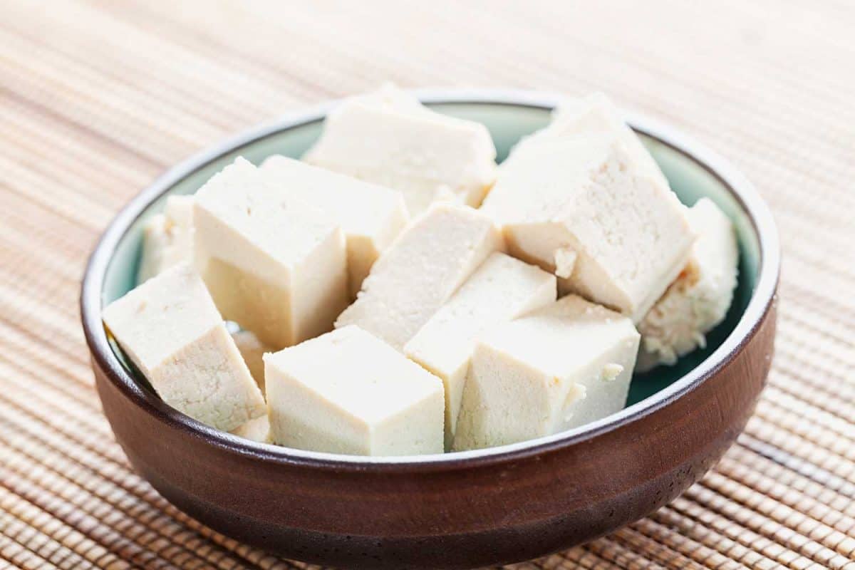 Cubes of tofu marinating in a small bowl