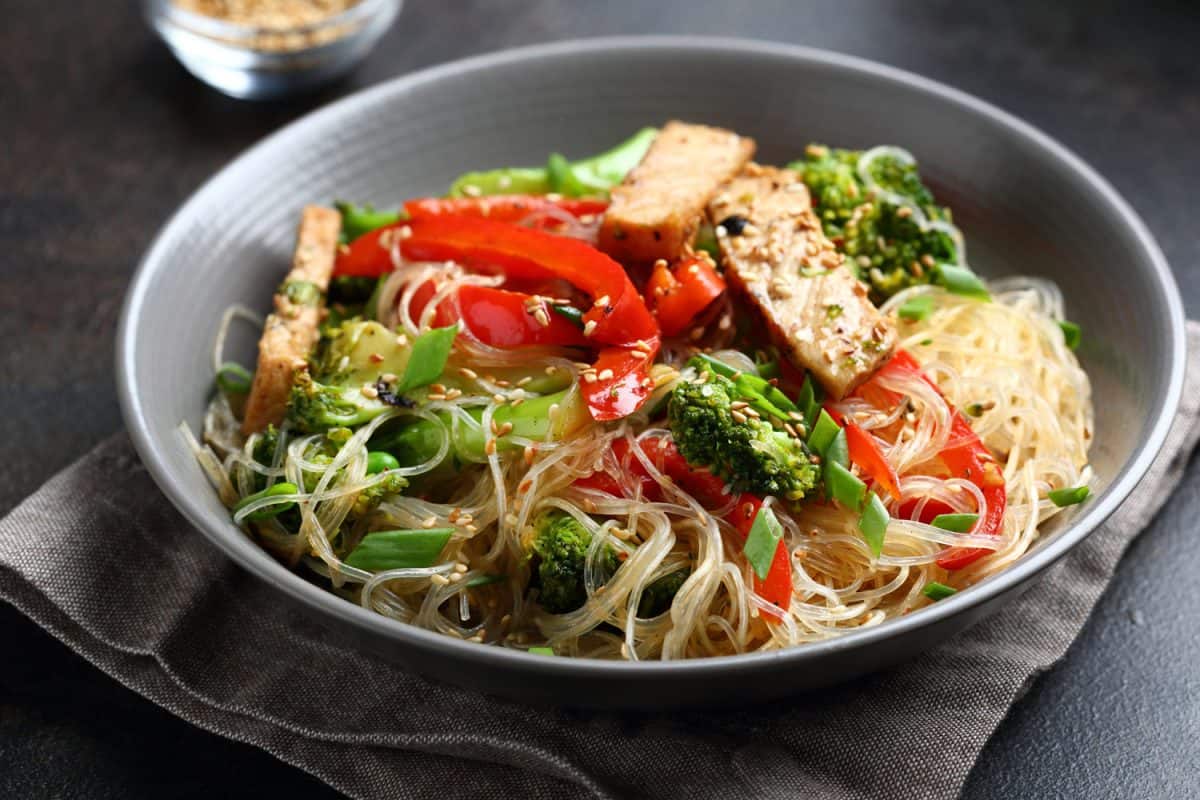 Delicious glass noodles with stir fry meat and other leafy greens on the sides