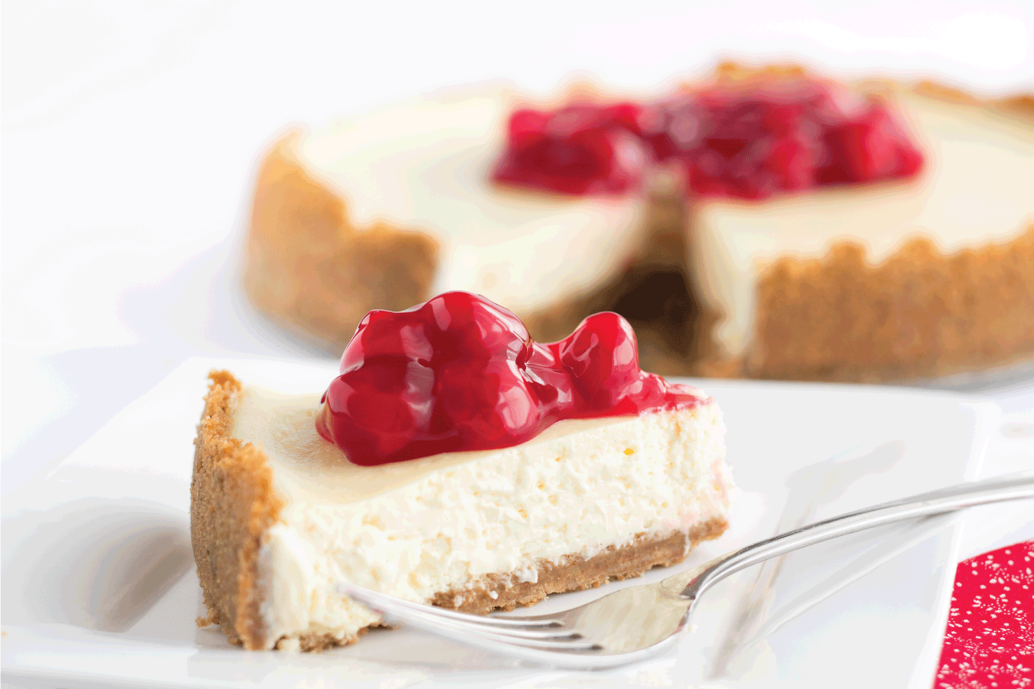 Delicious sweet red cherries top a smooth, creamy, decadent slice of cheesecake.