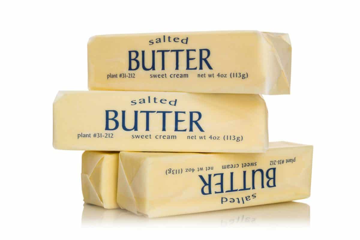 Delicious unwrapped salted butter on a white background