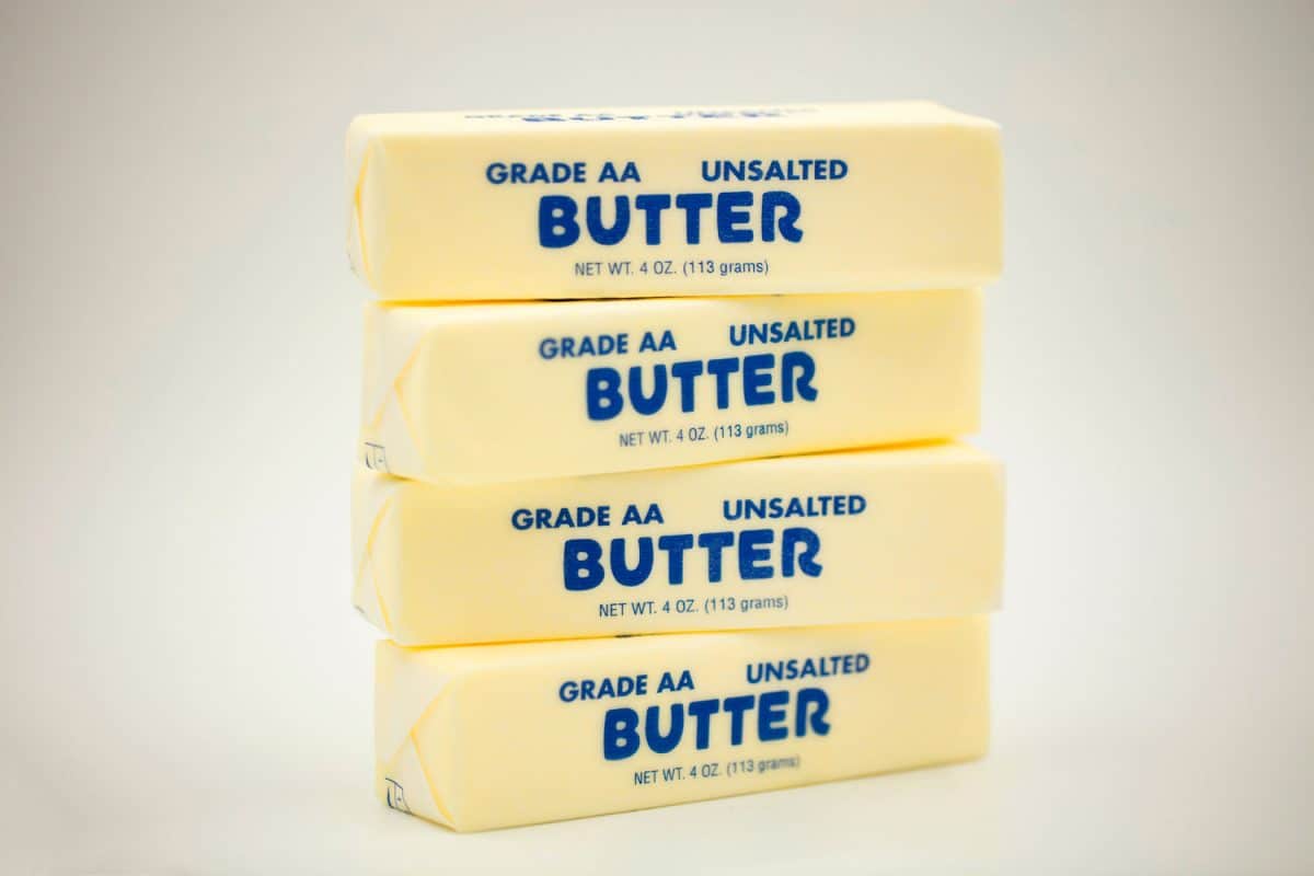 Four unwrapped unsalted butter on a brown background