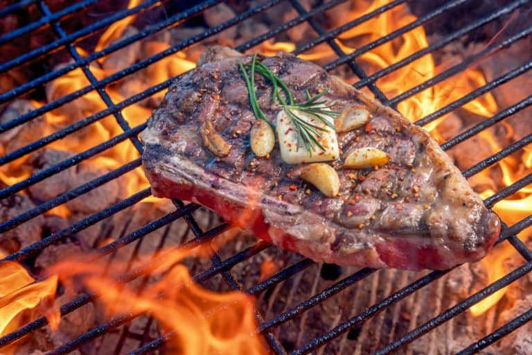Grilled Ribeye Steak On A Hot Charcoal Grill With Flames Topped With Sauteed Garlic Cloves A Pat Of Butter And Rosemary,Should You Add Butter To Steak?