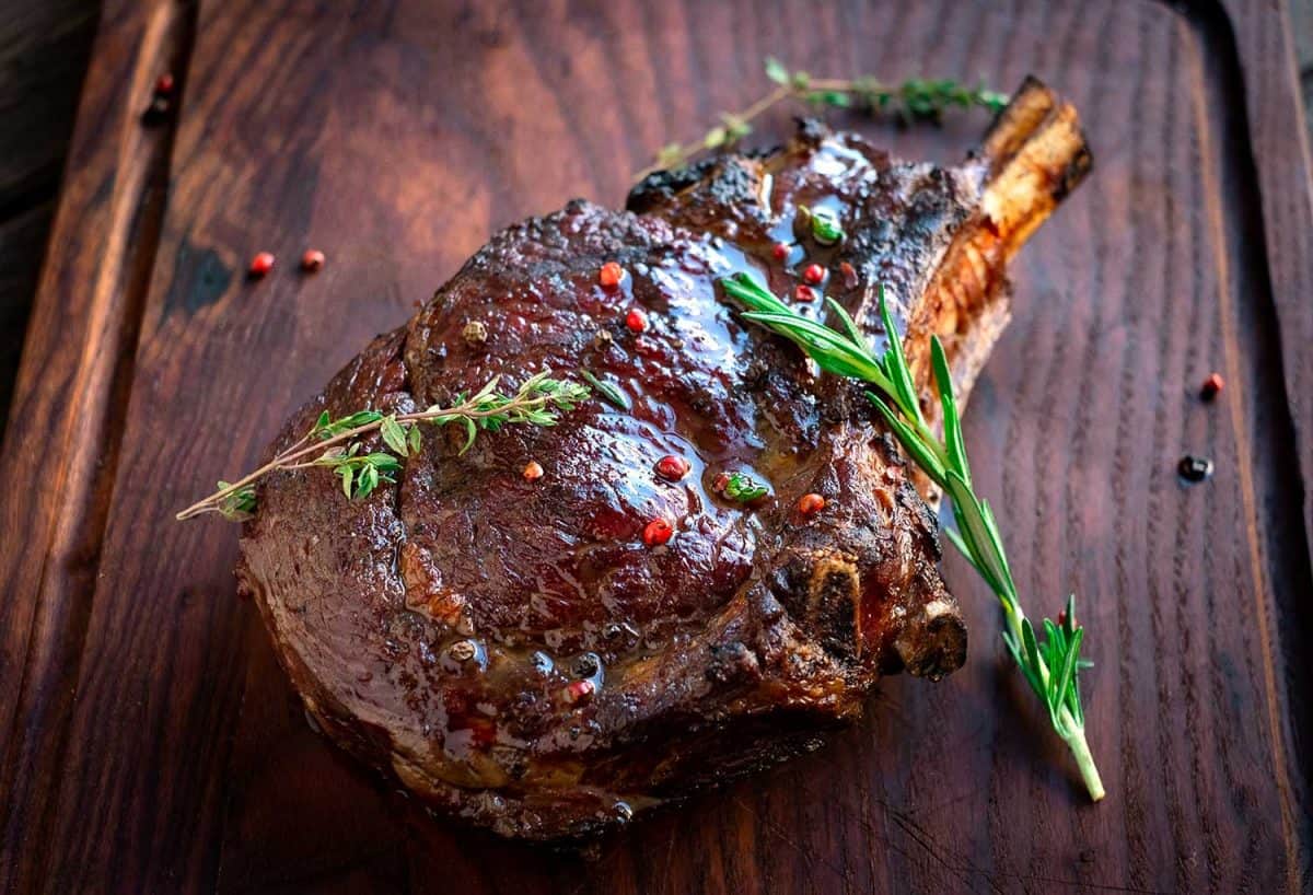 Grilled ribeye steak on bones on wooden board