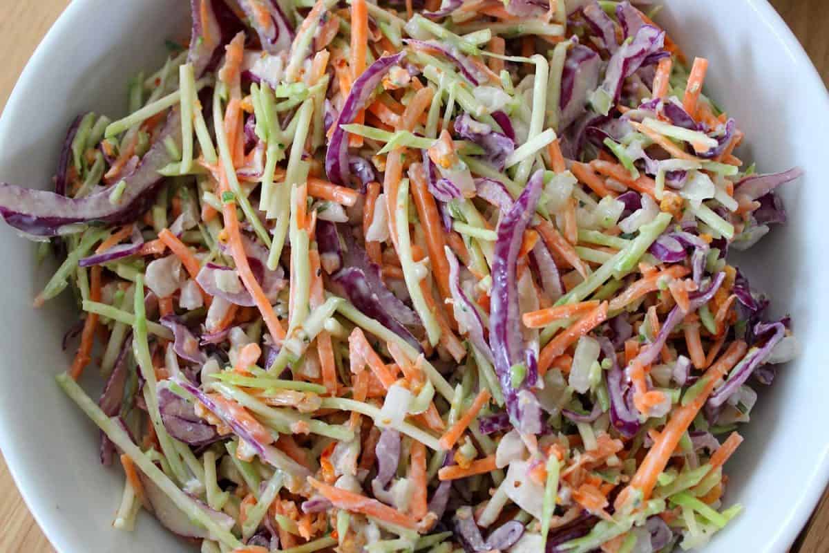 Homemade coleslaw, shredded red cabbage, grated carrot, sliced onion, and mayonnaise
