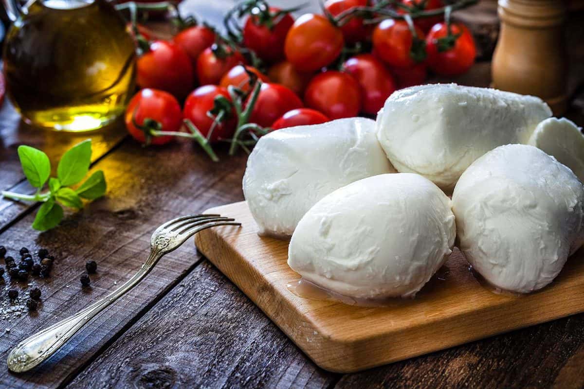 Mozzarella cheese on a cutting board shot on rustic wooden table