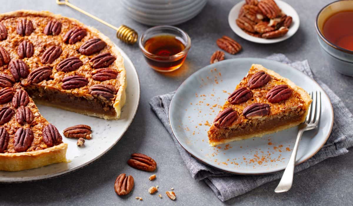 Pecan pie, tart with a cup of tea. Grey background.