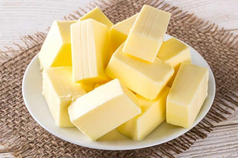 Rectangular pieces of fresh yellow butter on a white saucer over a white wooden table, Can You Add Salt To Unsalted Butter?