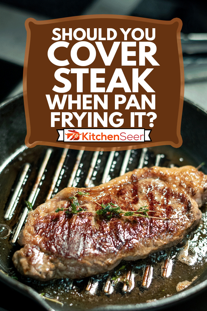 Appetizing roasted beef steak seasoned with fresh aromatic herbs on grill frying pan standing on electric stove in the kitchen, Should You Cover Steak When Pan Frying It?