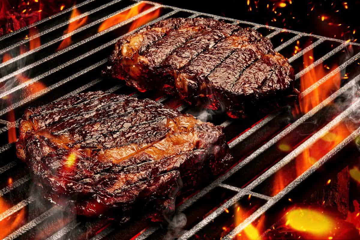 Steak being roasted from hot burning charcoal inside a portable grill