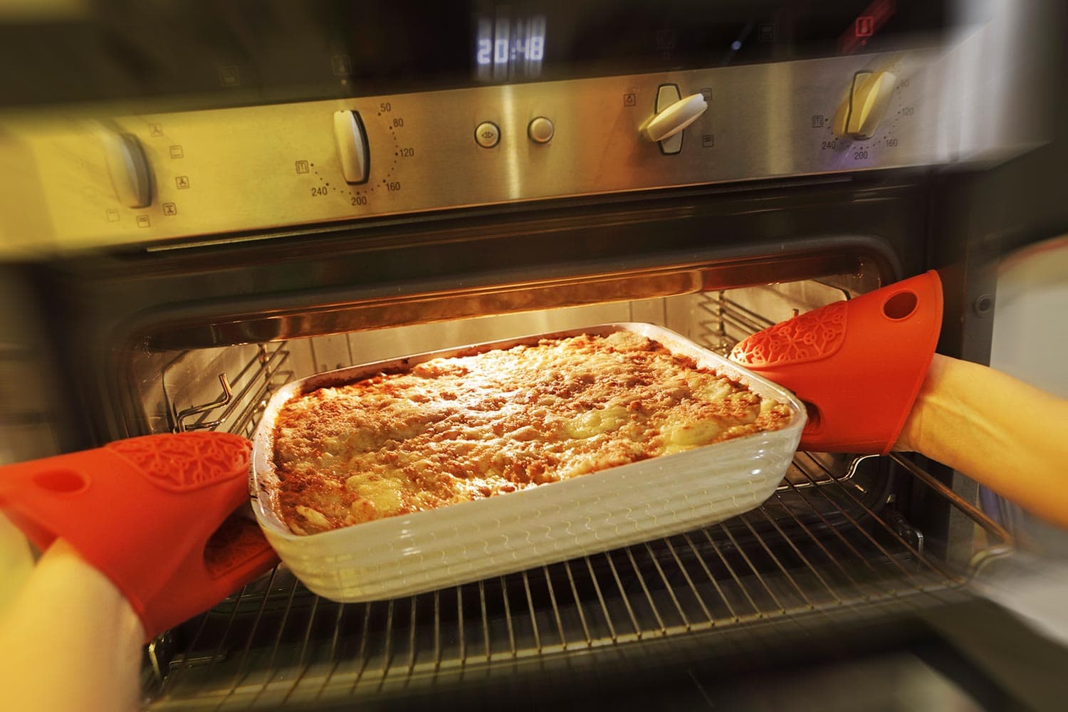 The lasagna is hot and illuminated by the oven light