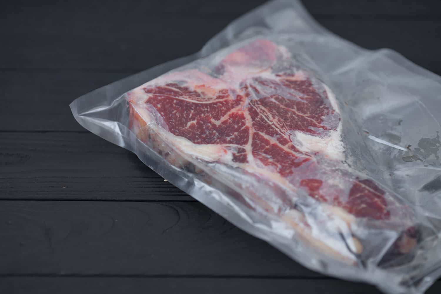Vacuum packed meat on old wooden background