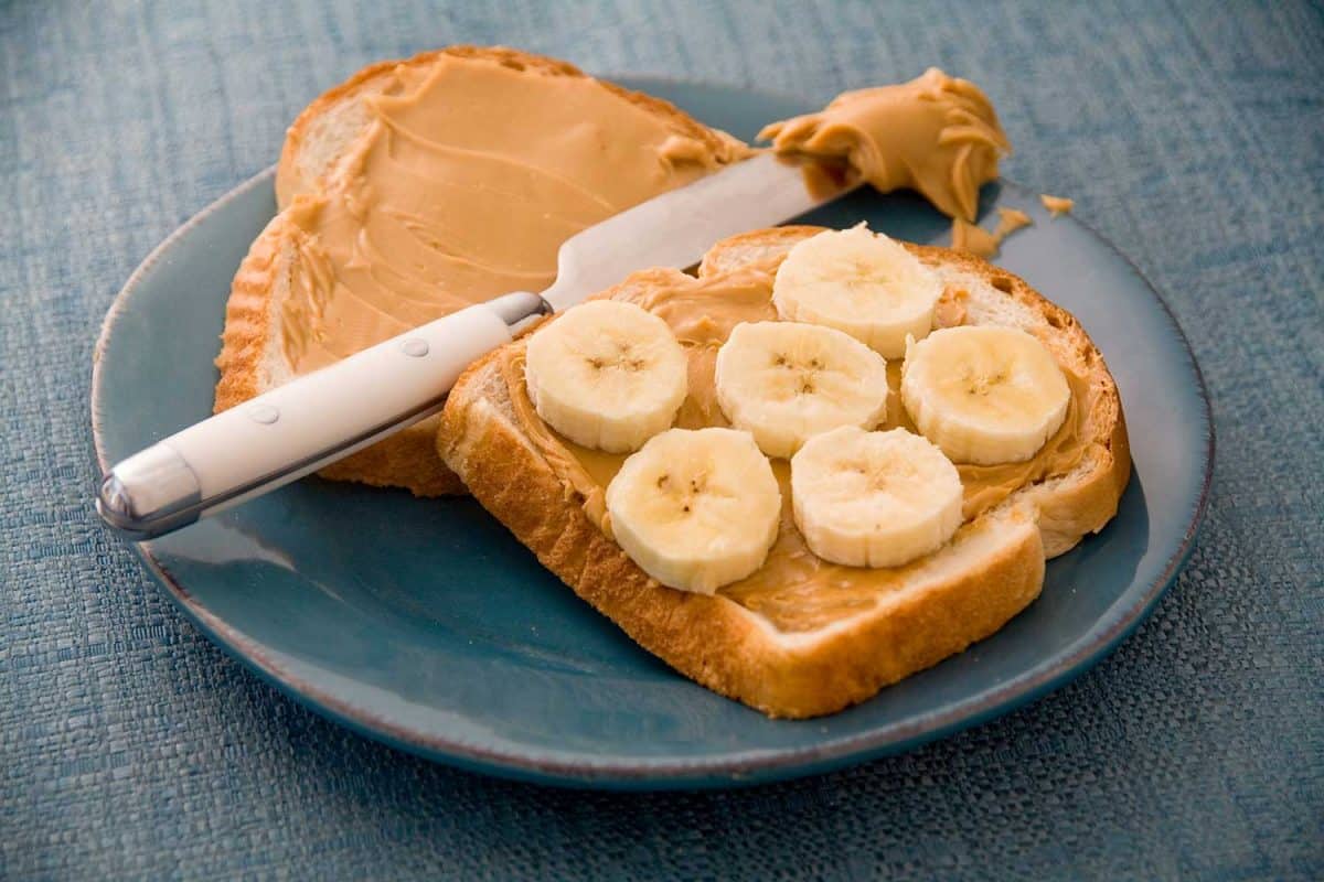 A peanut butter and banana sandwich on a blue plate and placemat
