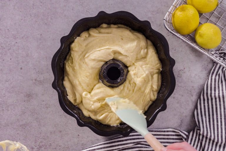 A woman making a bundt cake from a black colored bundt pan, How Full Should A Bundt Pan Be?
