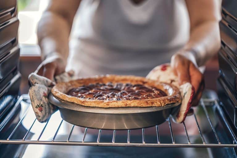 A woman taking off a freshly baked pecan pie out of the oven, Does Flour Burn In The Oven?