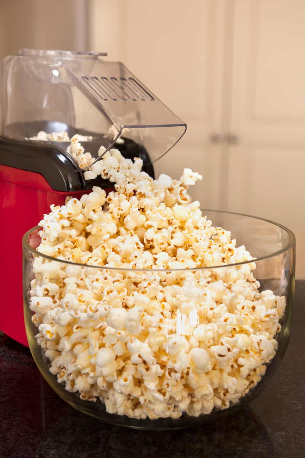 Bowl of popcorn with popcorn machine on a kitchen bench. Healthy home-made snacking.