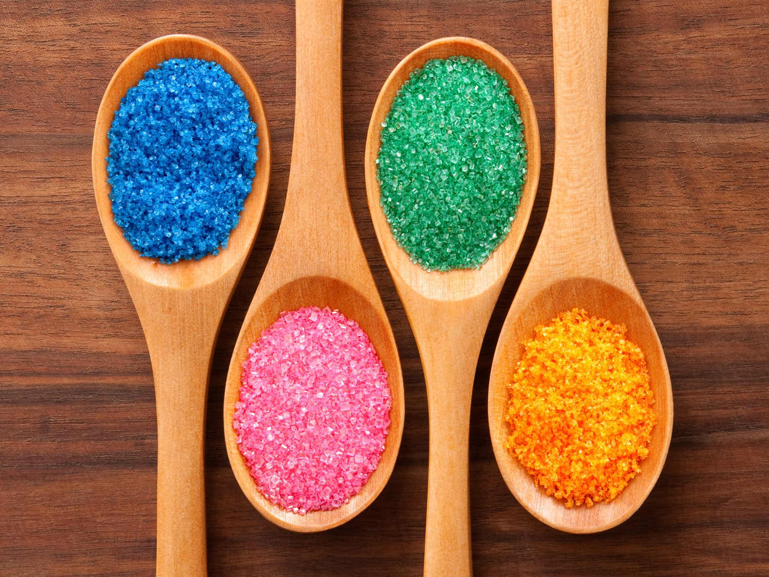 Four spoons with colored sugars