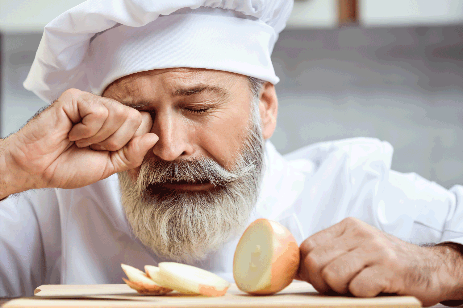 Master chef cutting onion with tears in his eyes
