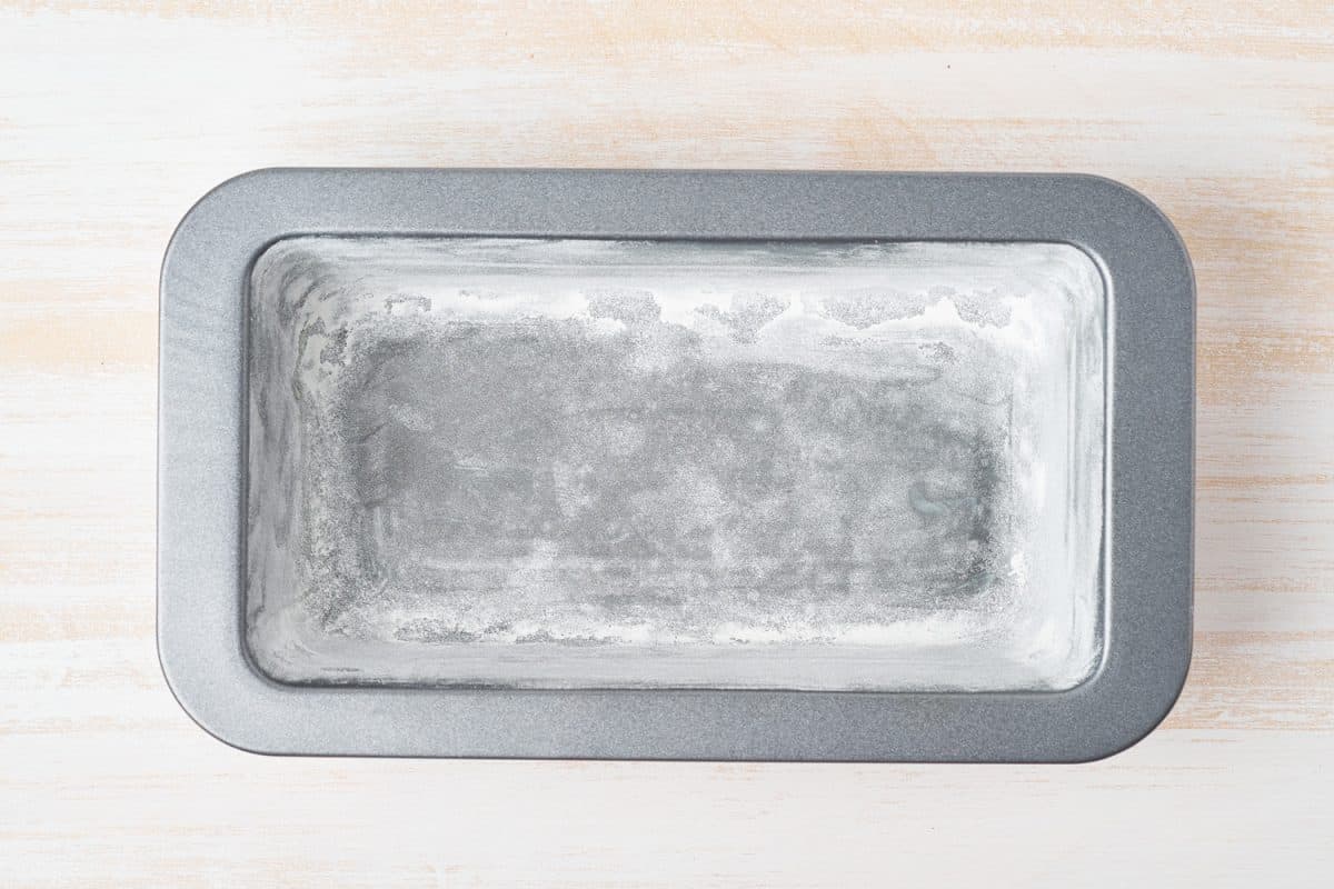 Oil greased and flour baking dish, bread loaf pan with butter