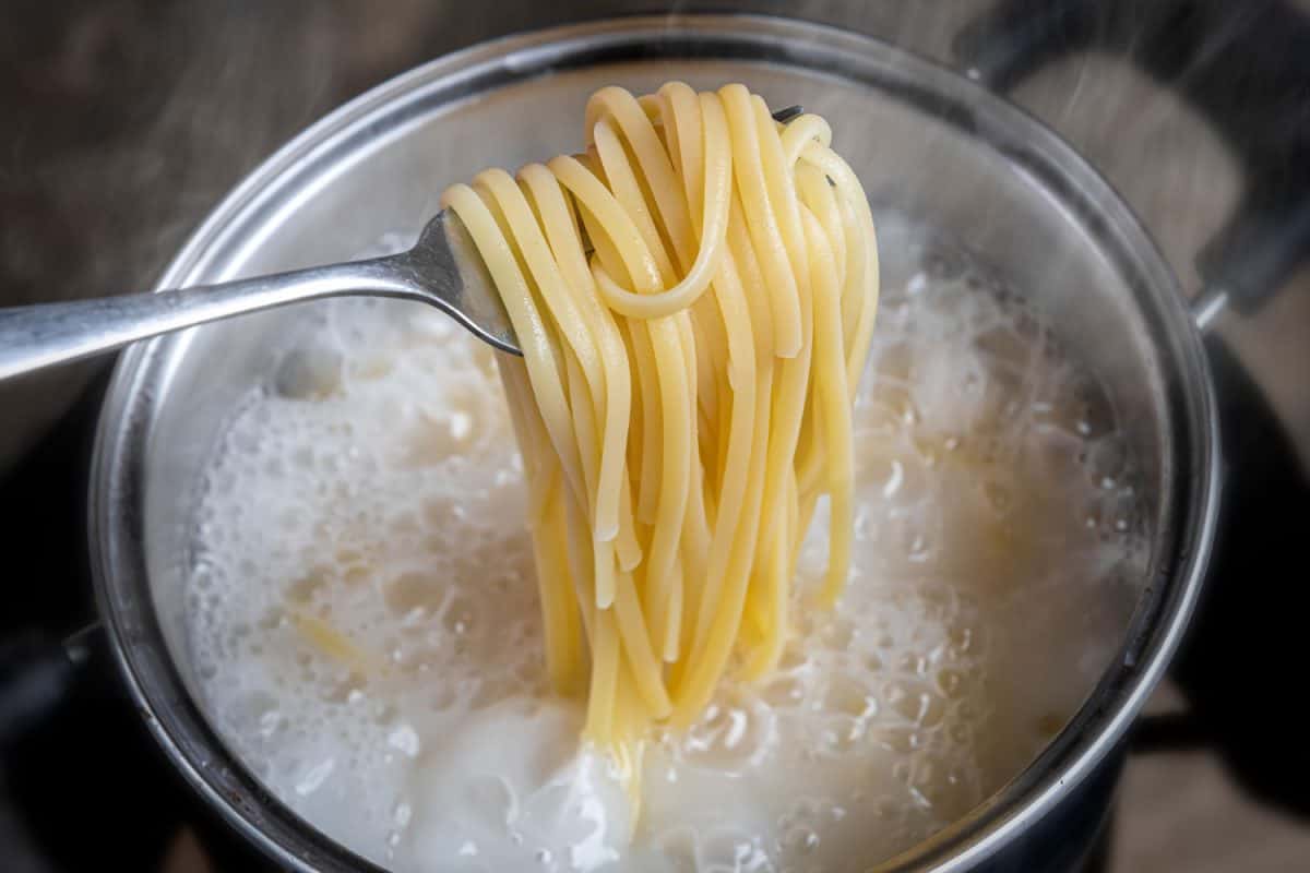 Pasta being cooked in a small stainless steel pot