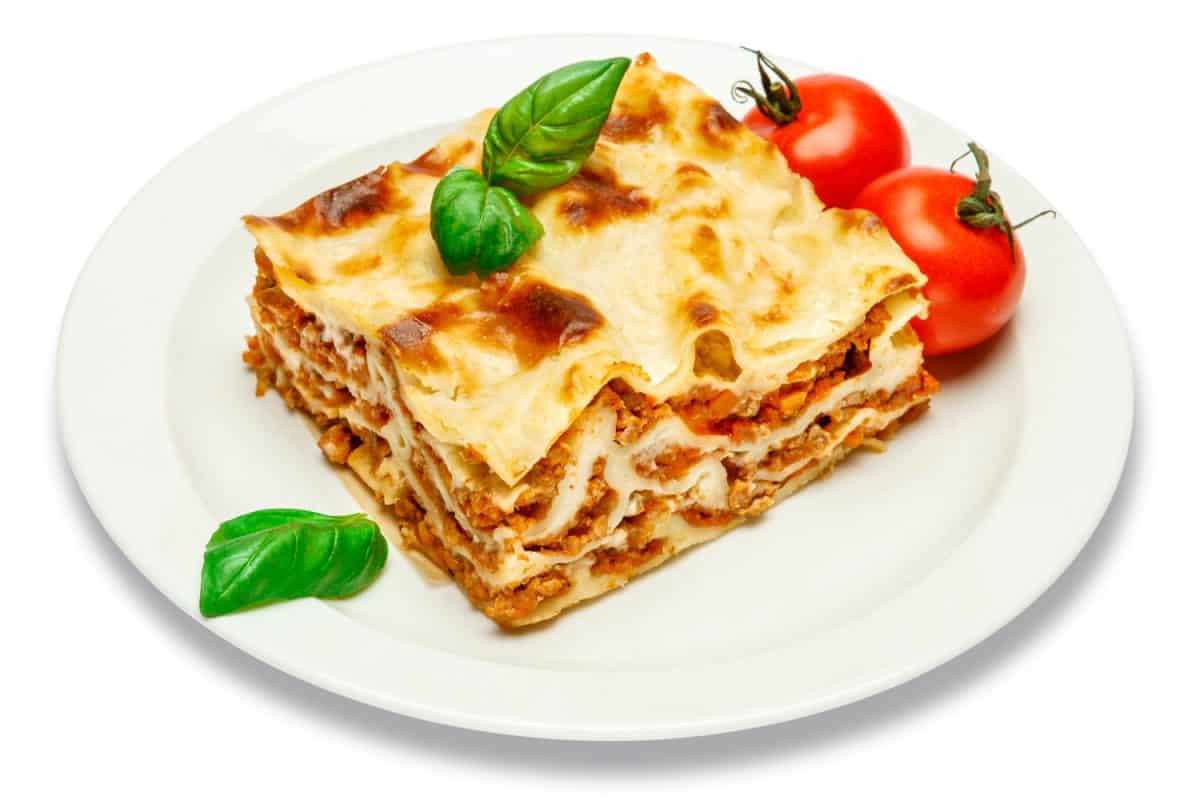 Portion of tasty lasagna isolated on white 