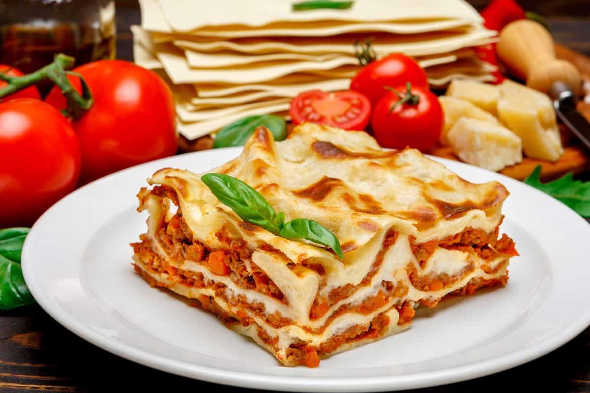 Portion of tasty lasagna on wooden background