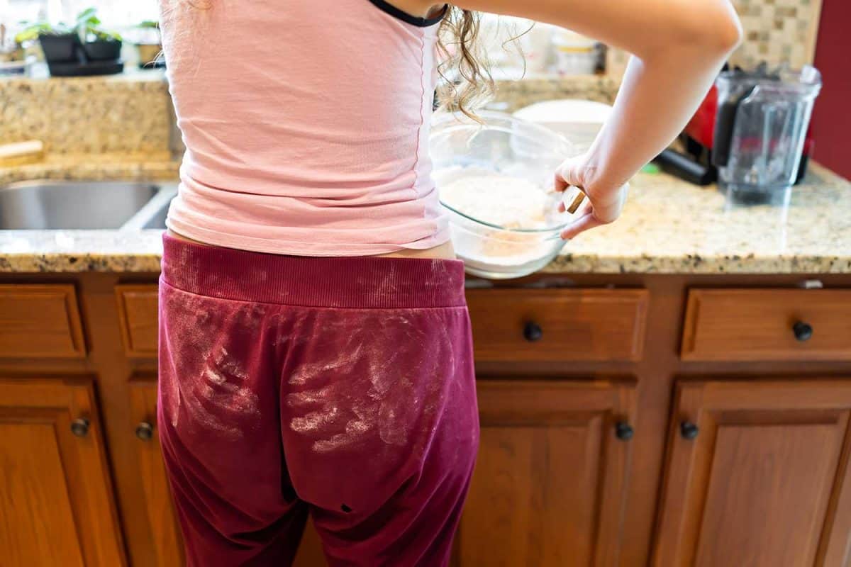 Sloppy young woman doing chores, preparing food in kitchen