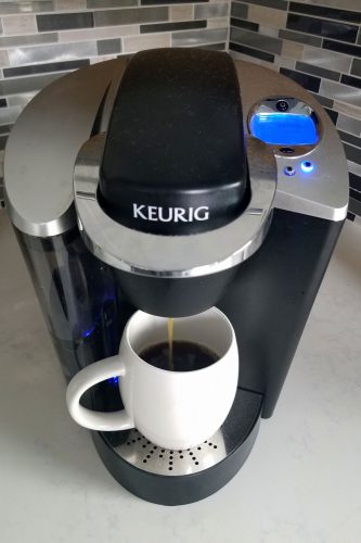 A-Keurig-coffee-maker-pouring-coffee-on-a-small-cup