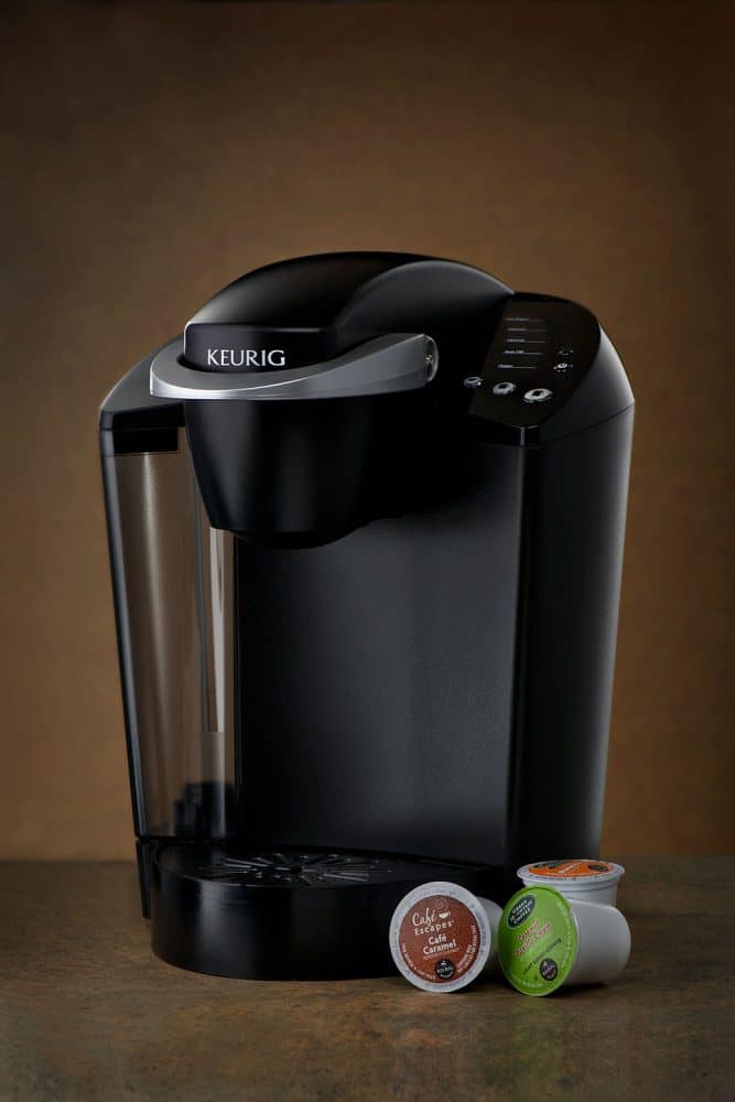 A Keurig coffee maker with three cup pods on the side