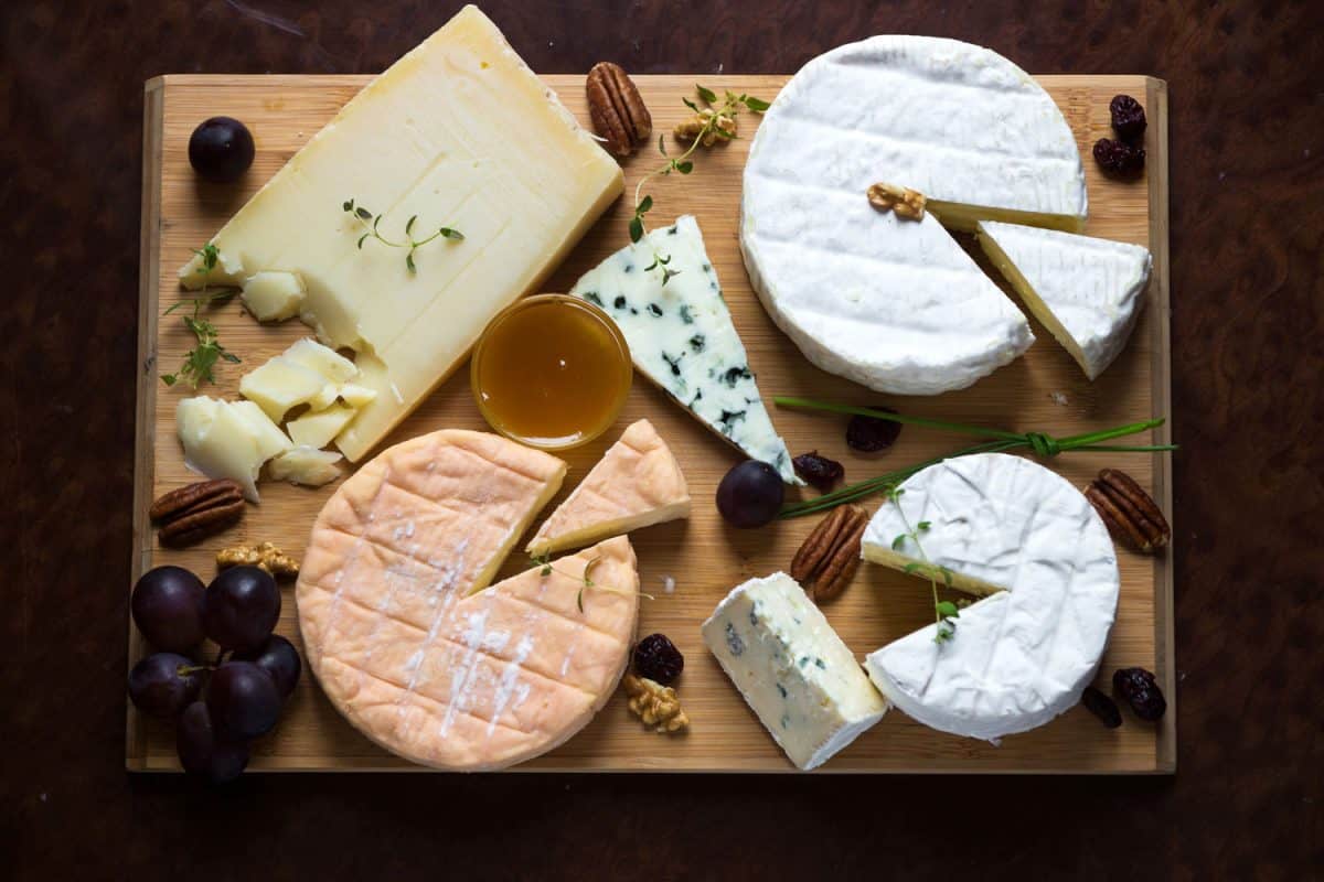 A cheeseboard served with different kinds of cheese, beans, honey, and herbs