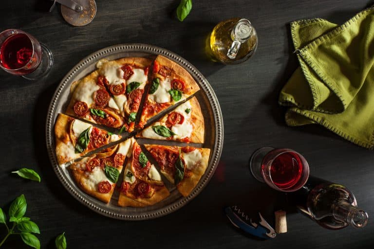 A delicious and perfectly cooked margarita pizza topped with sliced cherry tomatoes and mozzarella cheese, Do You Need To Grease A Pizza Tray? [Tips On How To Prepare One]