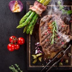 A deliciously roasted beef steak with oregano, asparagus, and small tomatoes on the side, What Oil Is Best For Grilling Steak?
