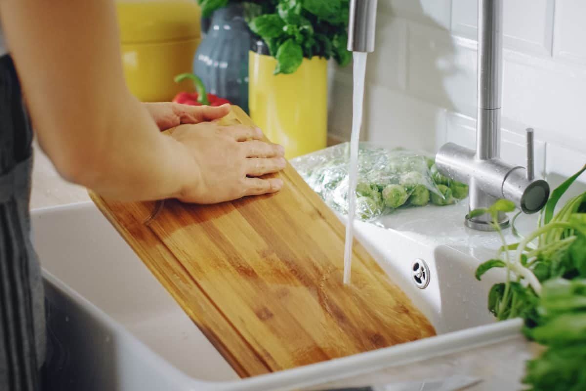 A woman washing her wooden cutting board on the sink