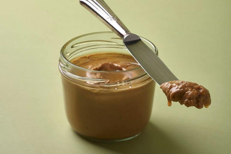 Almond butter in a jar and silver vintage knife with green background, Can Almond Butter Go Bad?