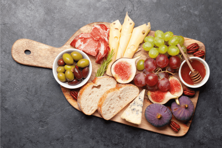 Antipasto plate with prosciutto, cheese, figs and grapes. Appetizer board. How Much Does It Cost To Make A Cheese Board