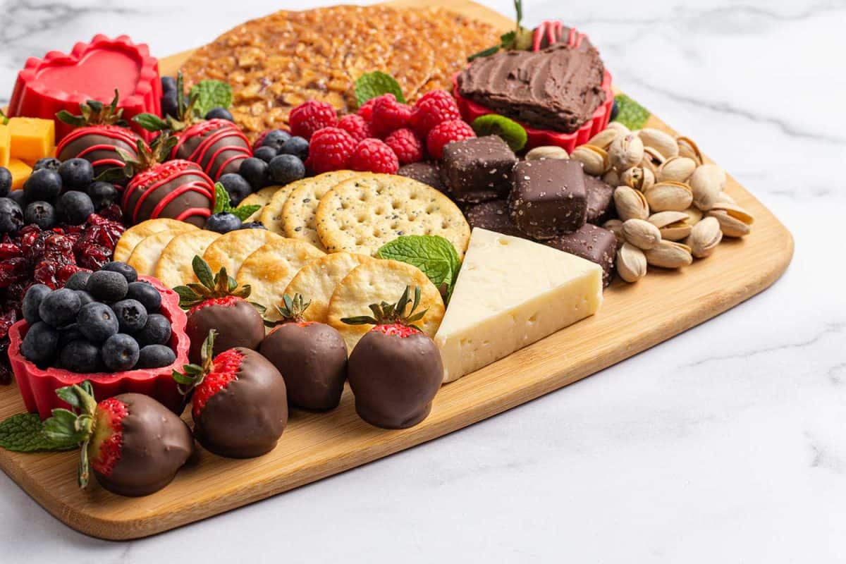 Chocolate covered strawberries and cheese sweet charcuterie board on a marble counter