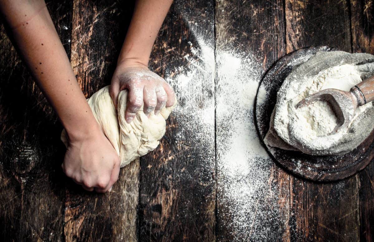 Dough background. A woman is preparing a dough. On a wooden table.