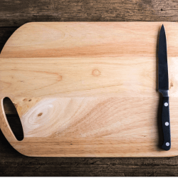 Empty-chopping-board-with-a-sharp-paring-knife-on-a-distressed-grunge-wooden-table-in-a-rustic-kitchen
