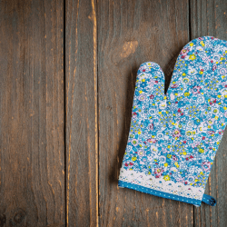 Floral oven mitten on wooden table. 9 Types Of Oven Mitts [And How To Choose]