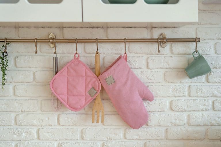 Kitchen glove, potholder, oven protection are hanging over white brick wall, 12 Types of Pot Holders [And How To Choose]
